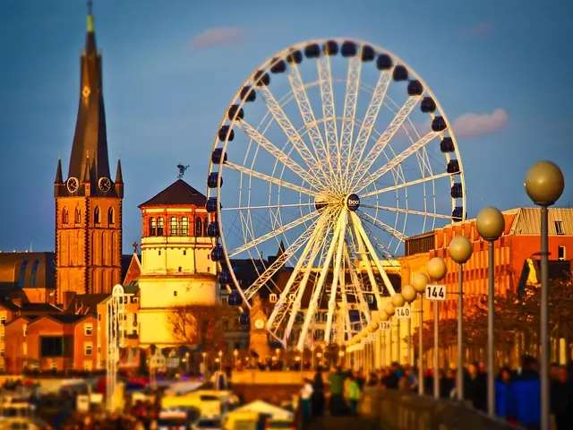 Ein großes Riesenrad steht vor einer Kirche, die im Hintergrund sichtbar ist