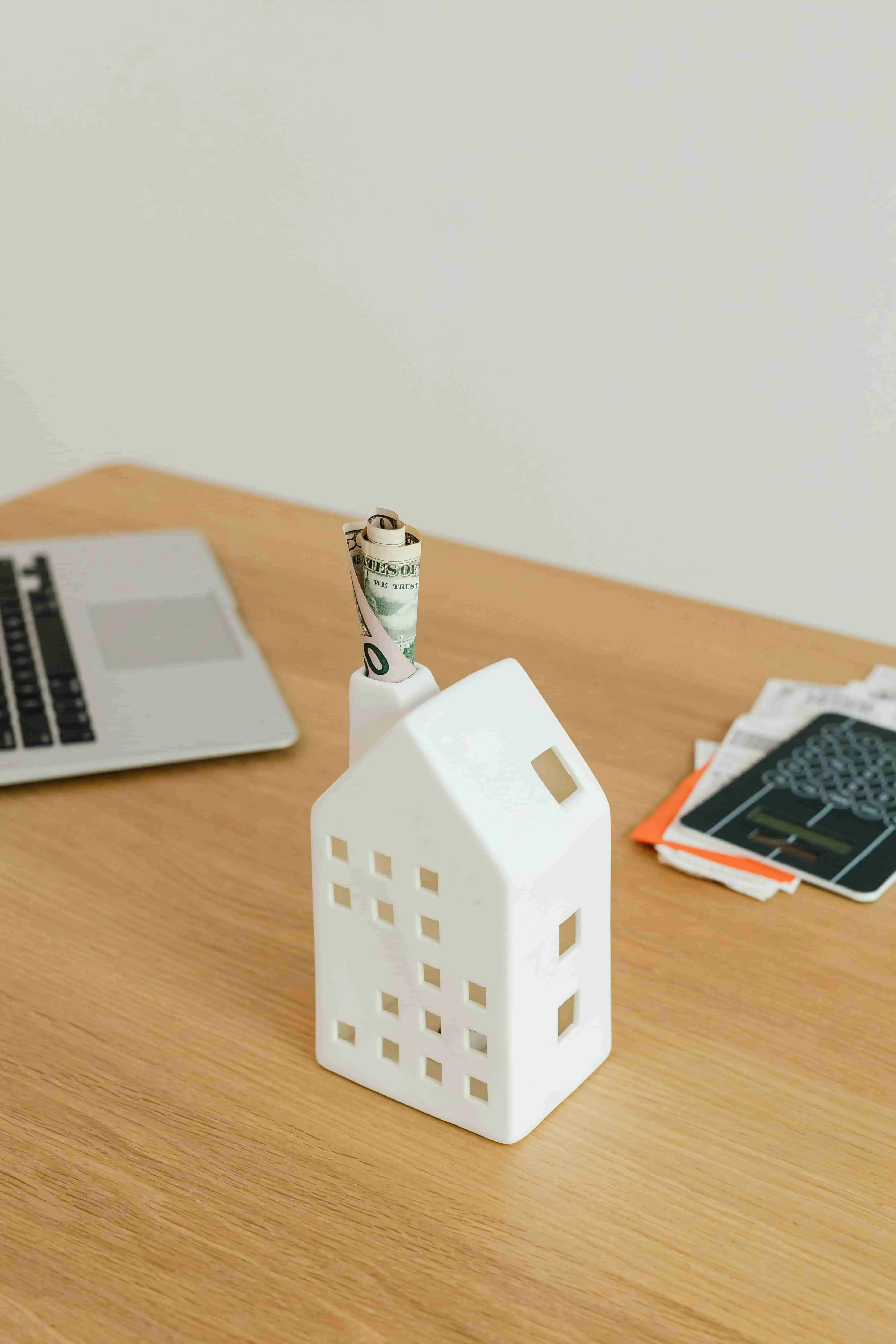 Schreibtisch mit Laptop und Modellhäuschen