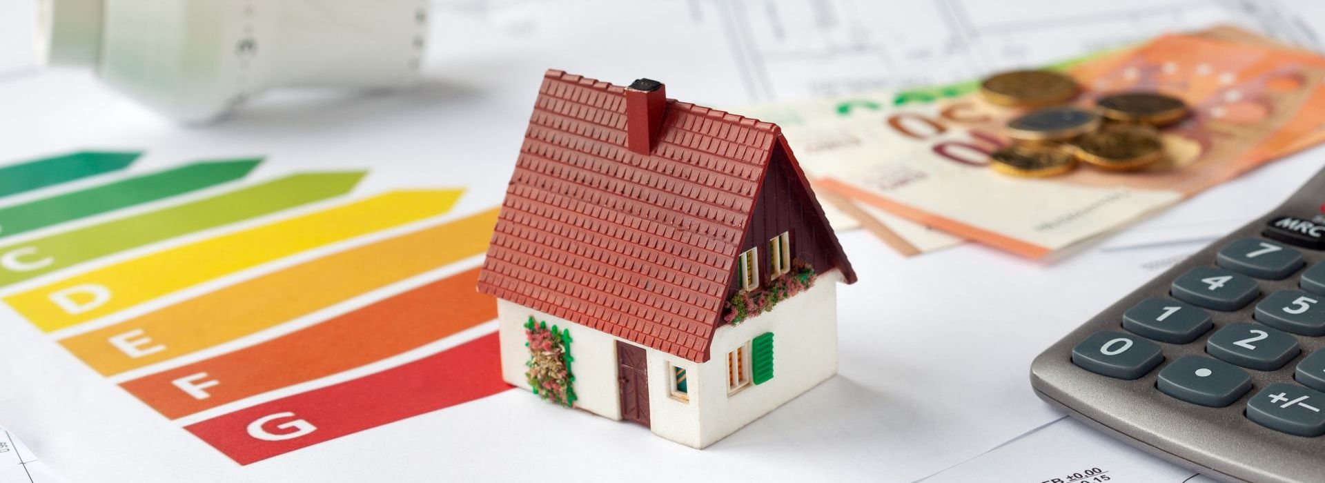 Symbolbild Energieberatung mit Bauplänen, Rechner, Geld und Thermostat - Beantragung von Fördermitteln zur energetischen Sanierung einer Immobilie