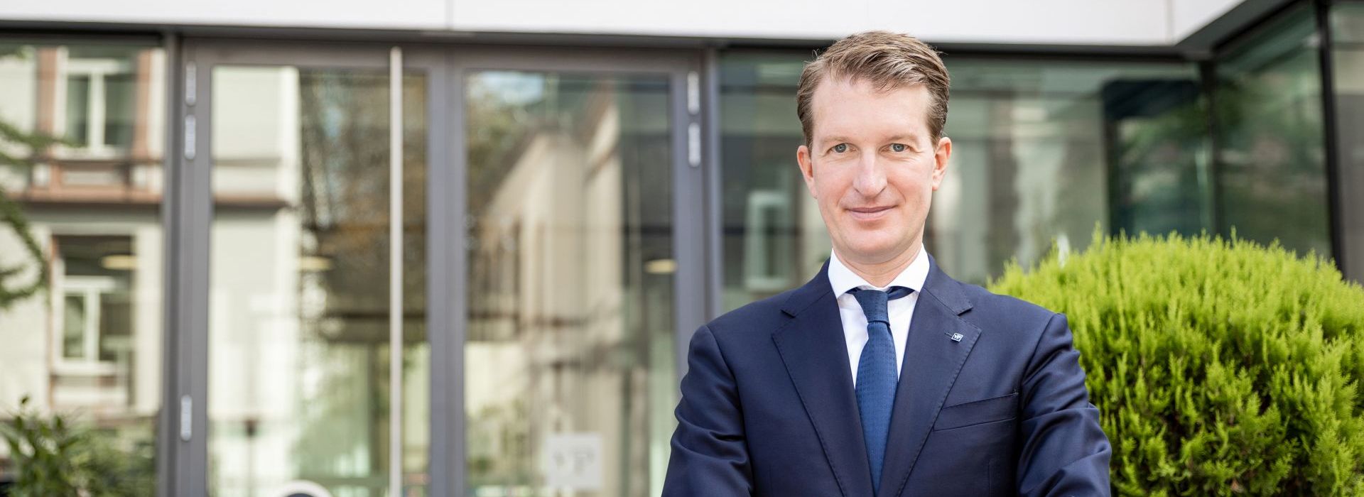 Mann im Anzug vor Unternehmensgebäude