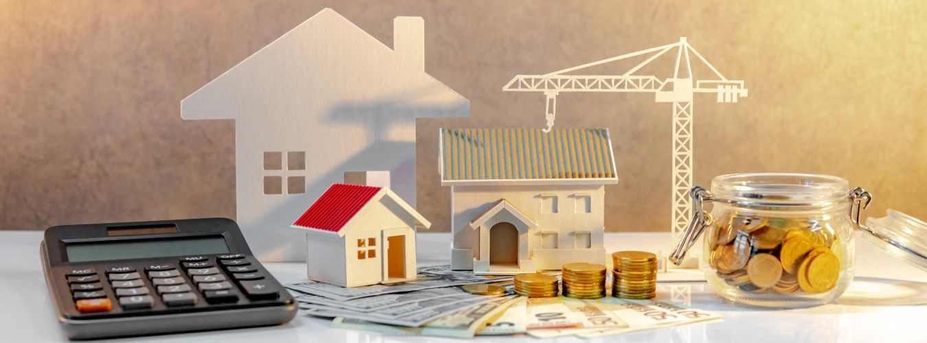 Immobilienentwicklung. Münzstapel auf internationalen Banknoten mit Taschenrechner, Haus- und Kranmodellen