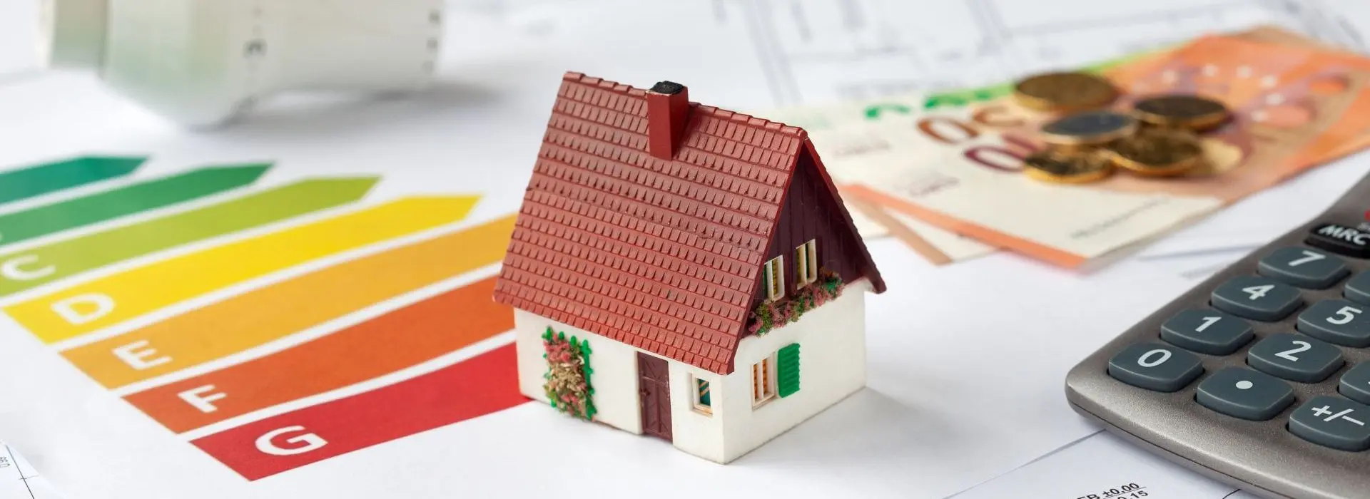 Immagine simbolica di una consulenza energetica con planimetrie, calcolatrice, denaro e termostato - richiesta di sussidi per la ristrutturazione ad alta efficienza energetica di un immobile