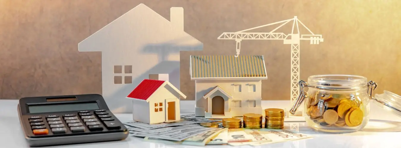 Sviluppo immobiliare. Pila di monete su banconote internazionali con modelli di calcolatrice tascabile, casa e gru