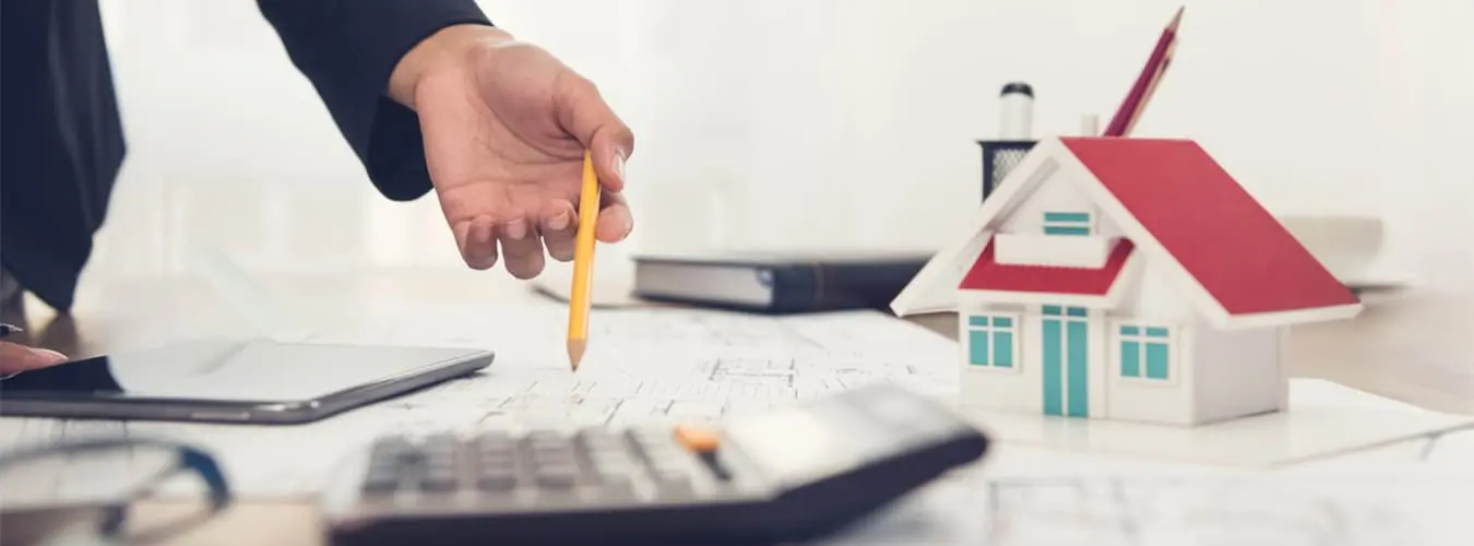 Scrivania con casa modello, calcolatrice tascabile e documenti